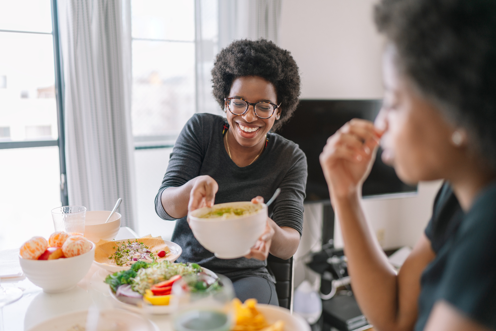 Two black women eating vegan food at home